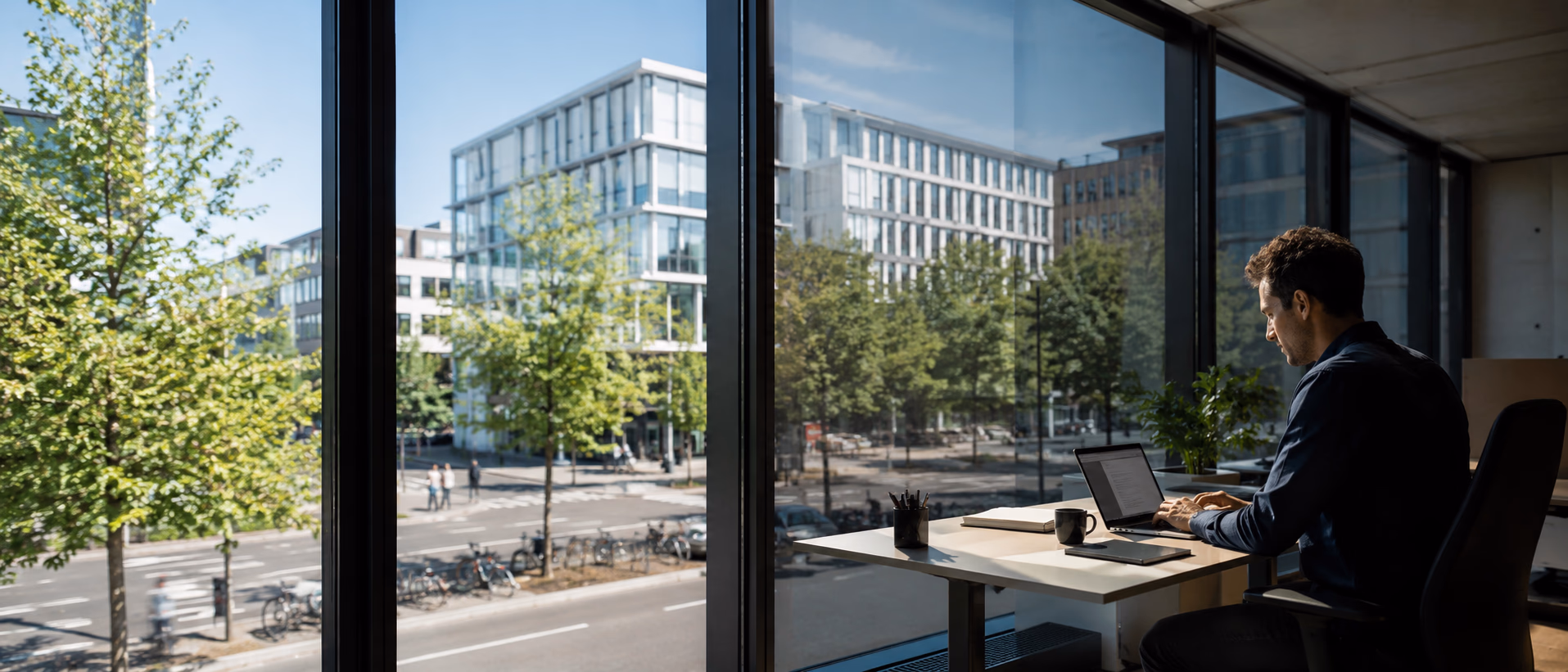 Mitarbeiter arbeitet am Schreibtisch ohne Blendlicht, Sonne draußen